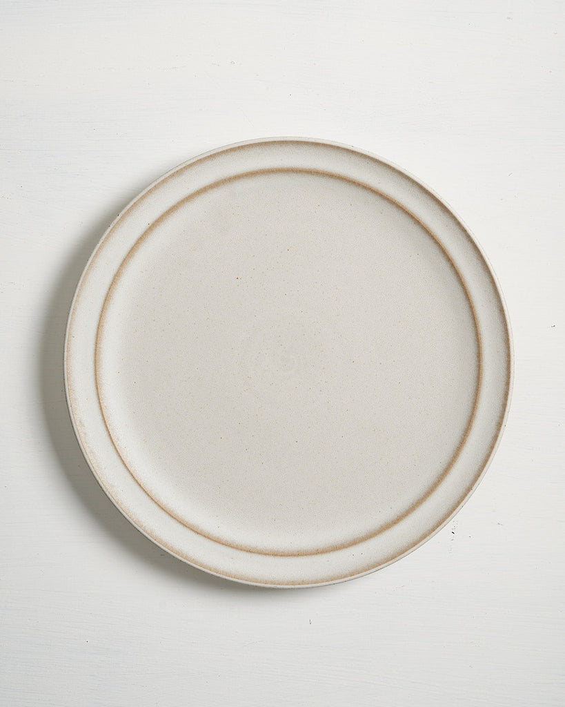 Beige ceramic Pillar Dinner plate with brown rim on a white background