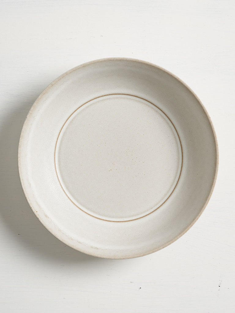 White ceramic Pillar low entree bowl with a gold rim on a white background