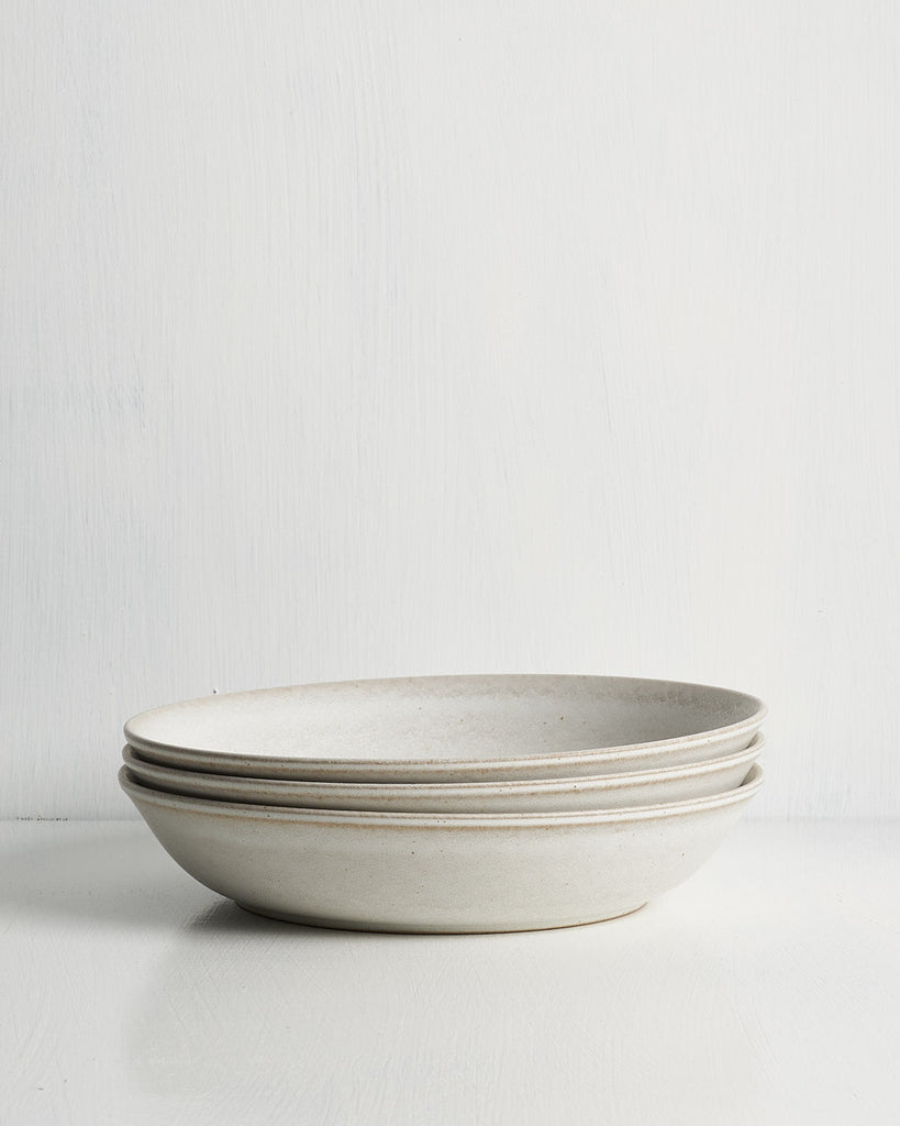 Stack of ceramic Pillar low Entree bowls on a white background