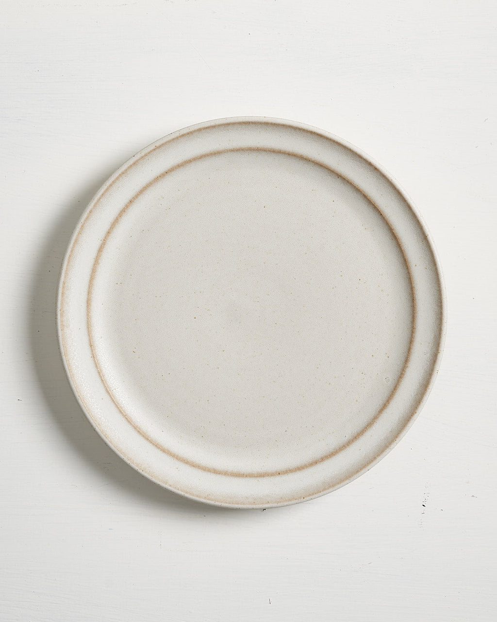Round ceramic Pillar Salad plate with a thin brown rim on a white background