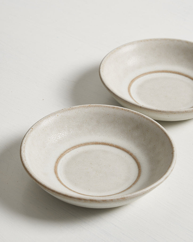 Two ceramic Pillar snack bowls with brown rims on a light gray background