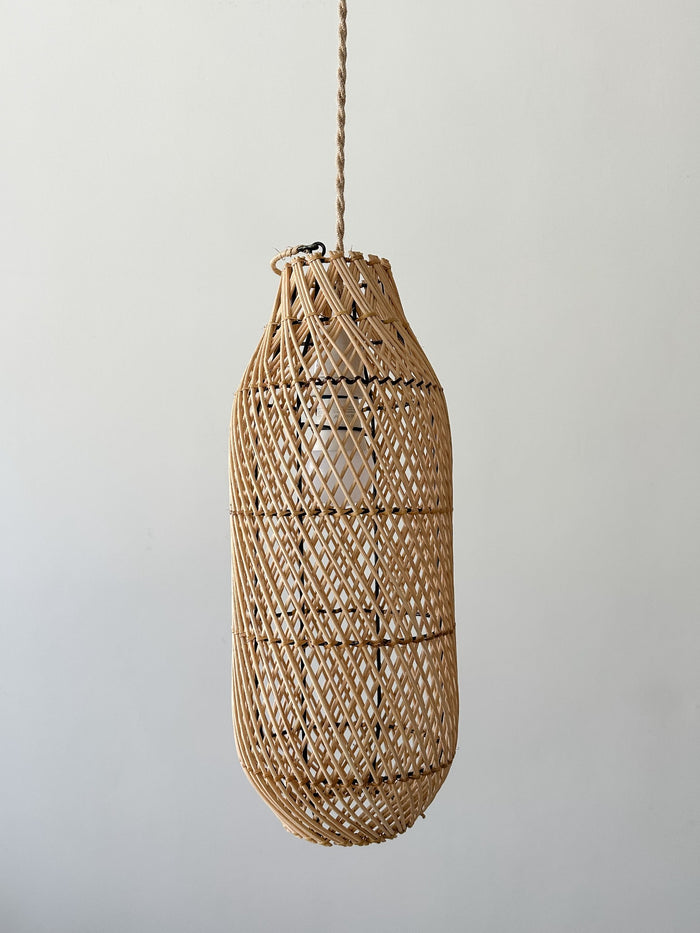  Front Product view of Bali Basket Swag Pendant hanging in front of a cream wall. -Saffron and Poe.