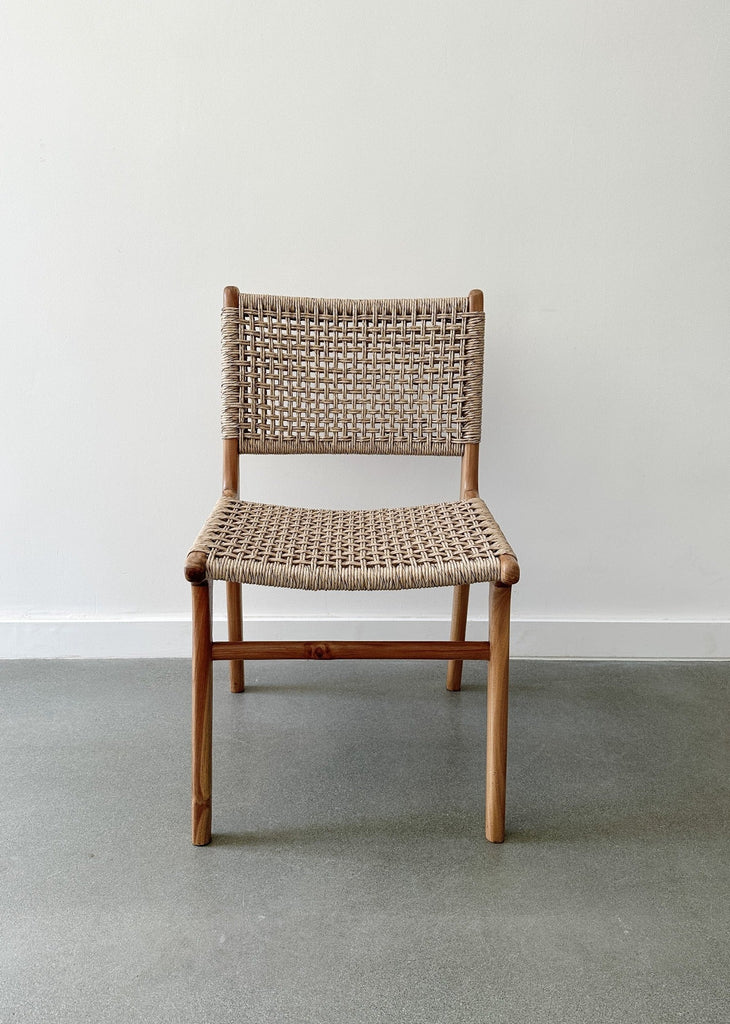 Front product view of the Marin Woven Faux Rattan Indoor/Outdoor Dining Chair on concrete flooring and a white wall backdrop. - Saffron and Poe