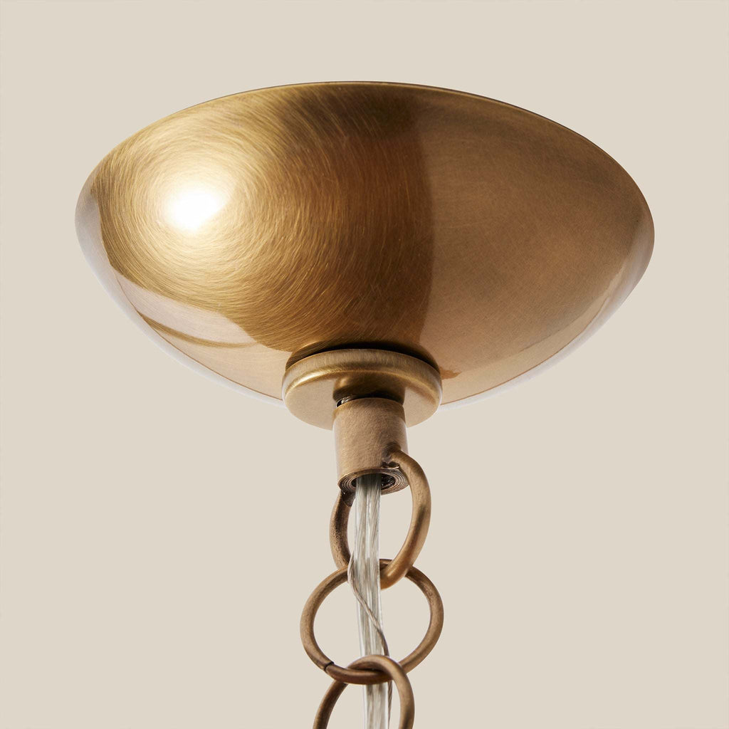Ravello Flushmount antique brass canopy and chain detail on a beige background.