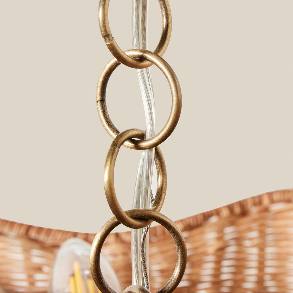 Close-up of a decorative light fixture with an interlocking antique brass chain on a neutral background.