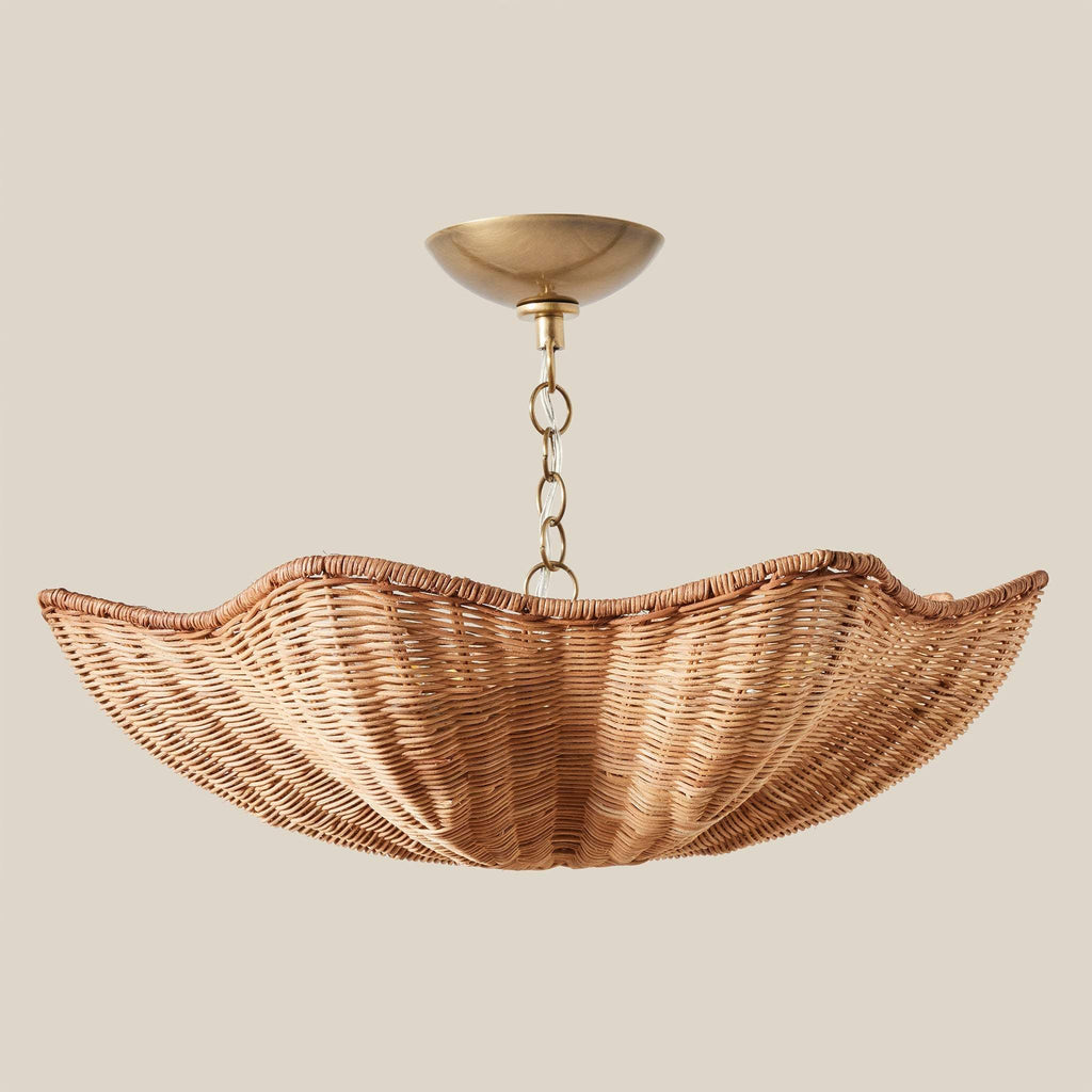Woven rattan Ravello flush-mount light fixture with a scalloped shade, suspended from an antique brass ceiling canopy and chain against a solid beige background.
