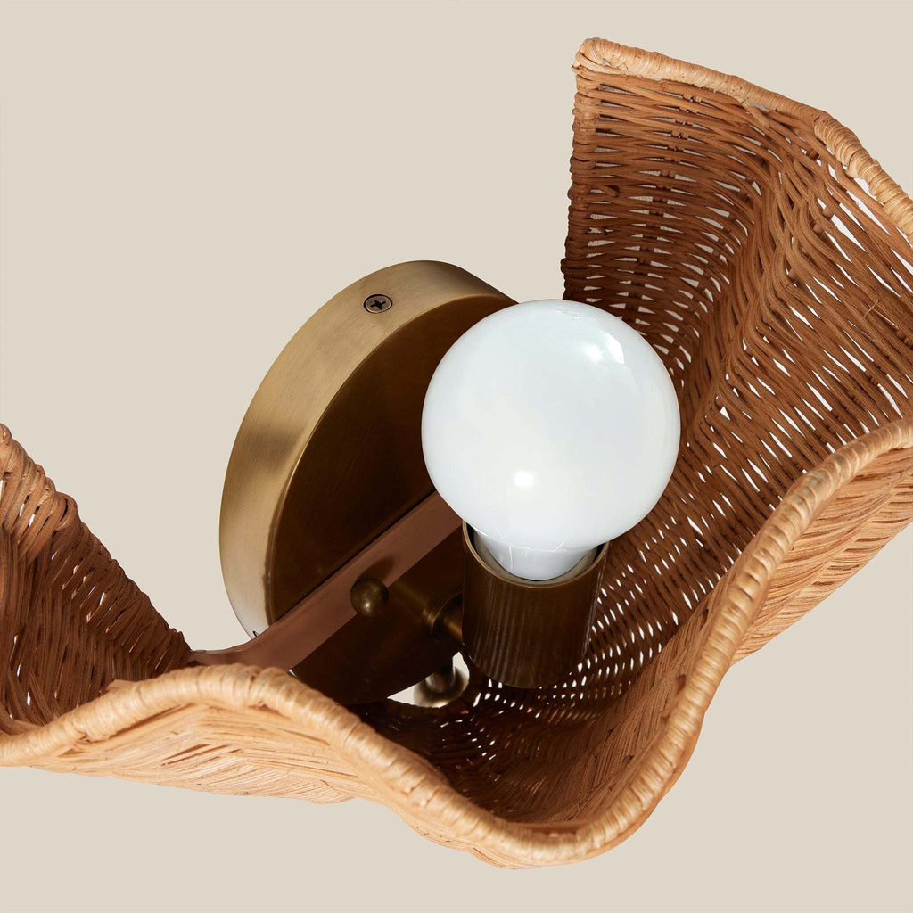 Wicker Ravello wall sconce with a white light bulb on a beige background
