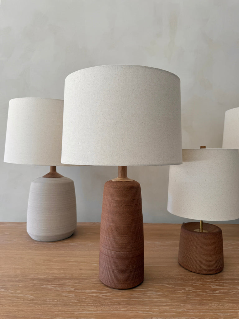 Ostuni, Ravello and Pienza Ceramic Table Lamps with oatmeal linen shades grouped on a white oak table. - Saffron + Poe
