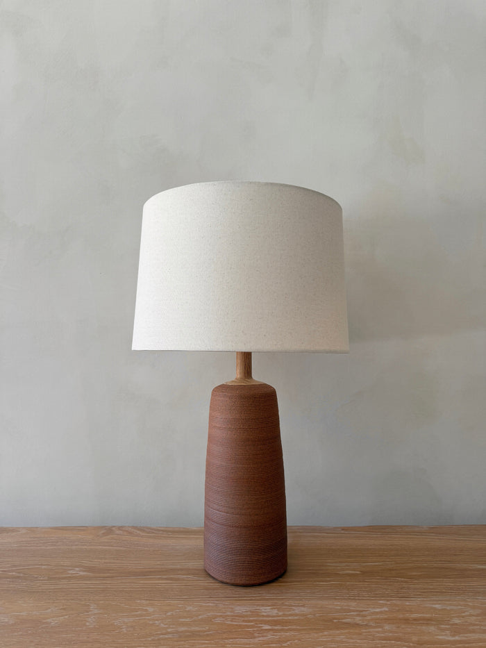 Ravello Ceramic Table Lamp in Terracotta with oatmeal linen shade on a white oak table against a limewashed wall. - Saffron + Poe
