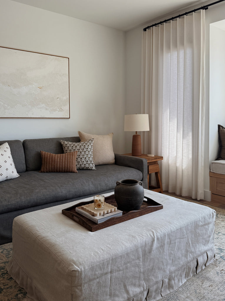 Ravello Ceramic Table Lamp in Terracotta with oatmeal linen shade in a living room with a blue sofa. - Saffron + Poe