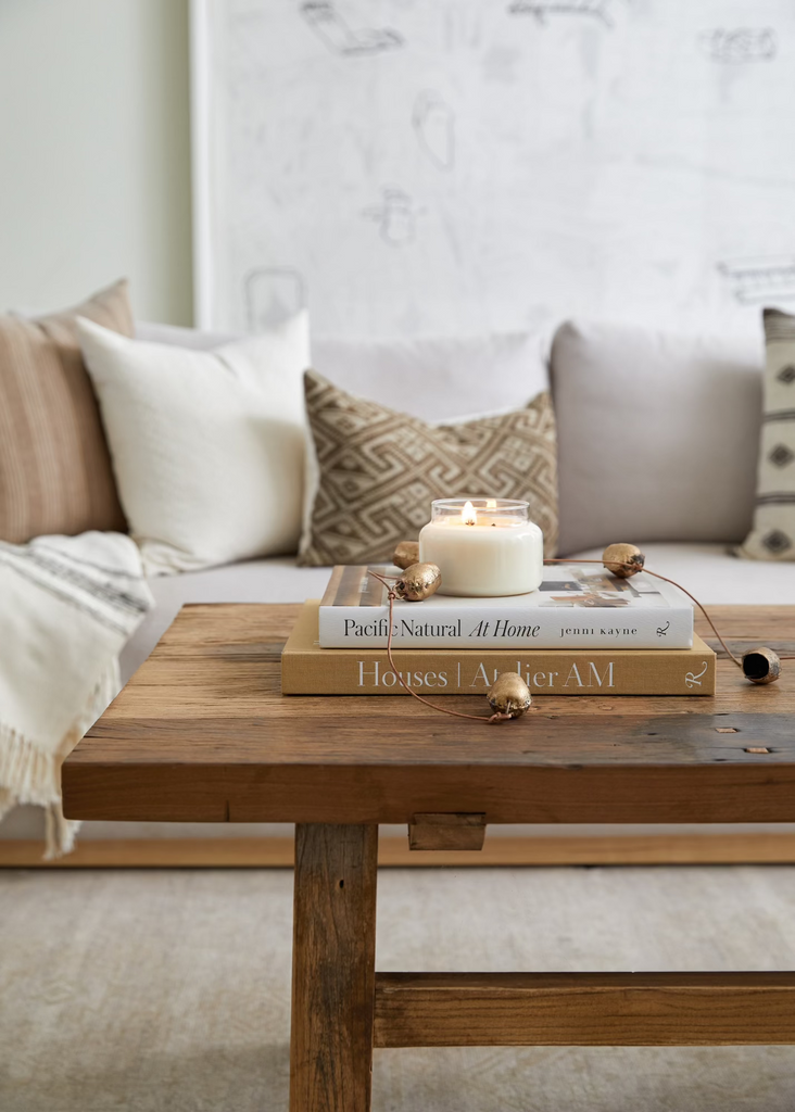 Cozy living room with a wooden coffee table, a string of bells, books, and a candle.