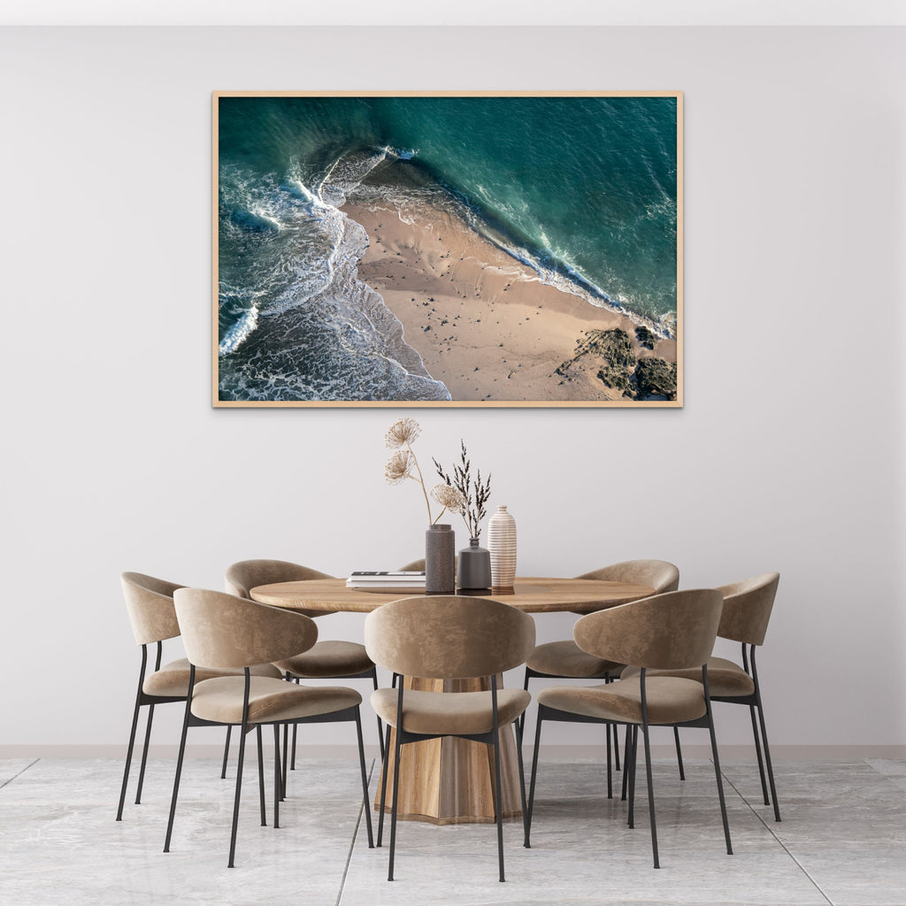 Aerial photo of the aqua blue ocean against a sandy shore in a room by Mika Street for Saffron and Poe