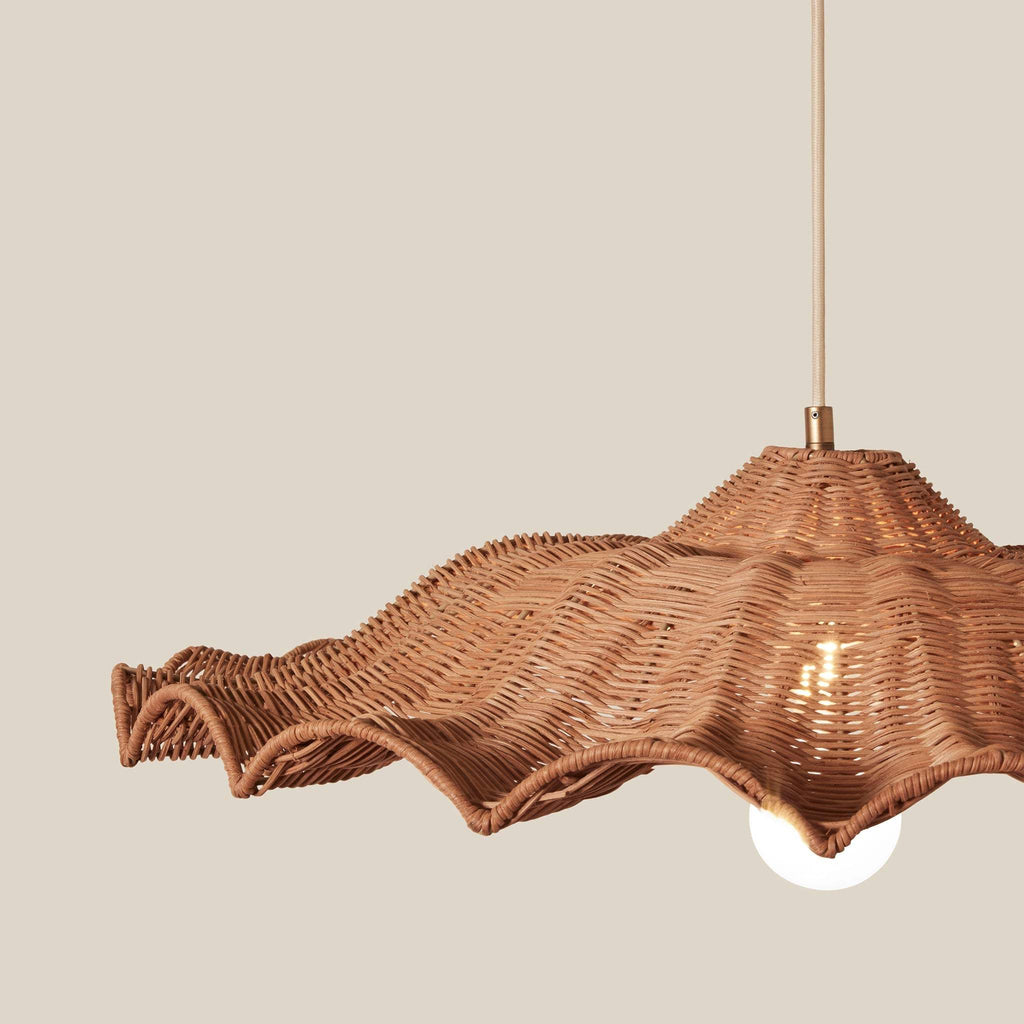 Savannah Large wicker pendant light with a wavy, scalloped edge and a warm brown woven texture, shown against a solid beige background with a glowing bulb inside.