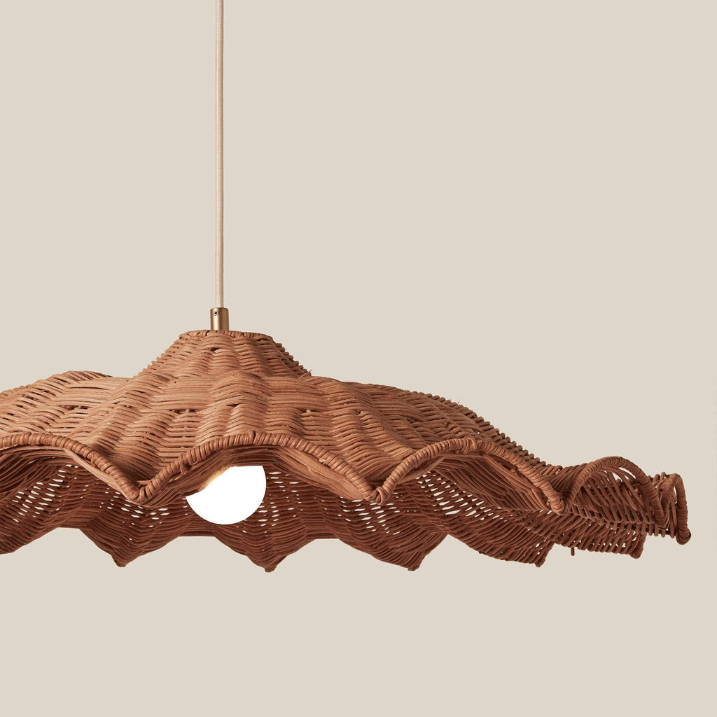Savannah Large wicker pendant light with a wavy, scalloped edge and a warm brown finish, suspended by a thin cord against a solid beige background.