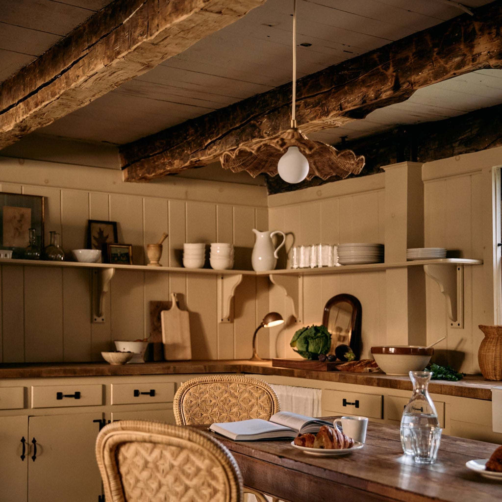 Savannah Pendant in a cozy European-styled kitchen with wooden beams, shelves with cookware, and a table set for breakfast.