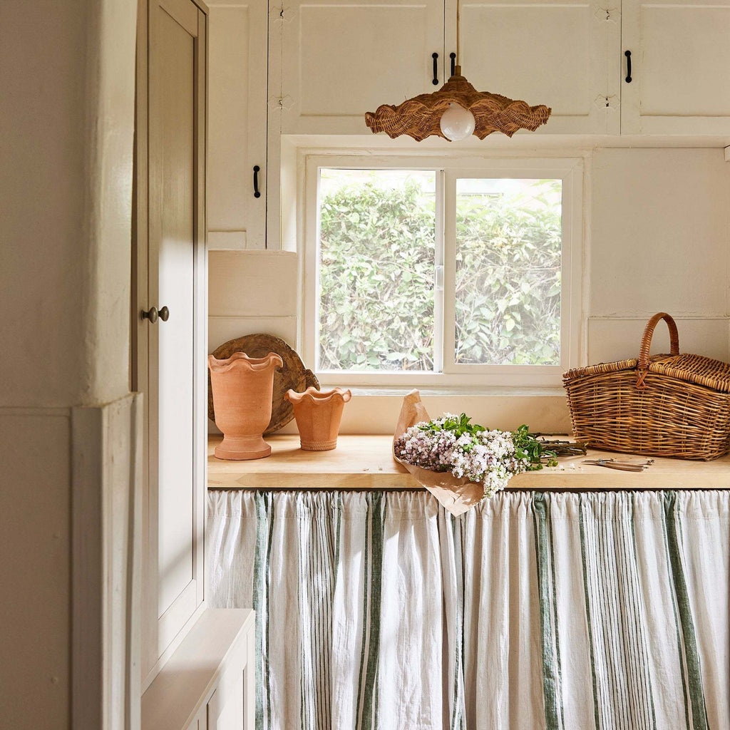 Savannah Pendant over a kitchen counter with a window, decorative items, and a striped curtain under countertop.
