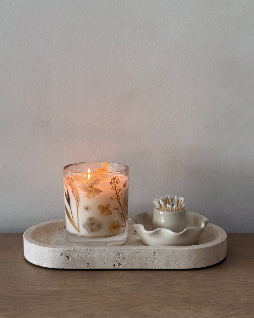 Candle with floral design on a stone tray with a white background