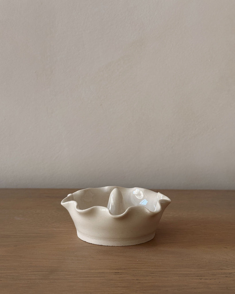 White ceramic dish with scalloped edge on a wooden surface