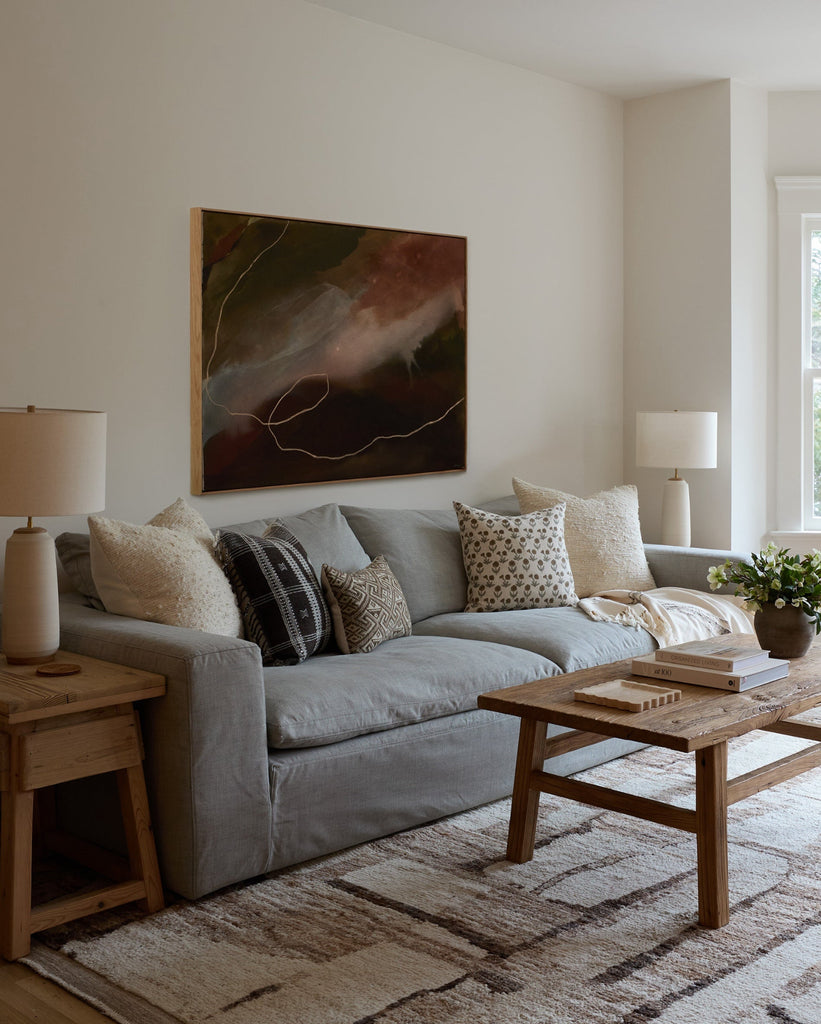 Living room with a gray sofa, wooden coffee table, and abstract painting on the wall.