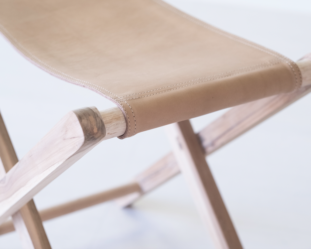 Beige leather folding stool with teak frame, minimalist wooden accent seat