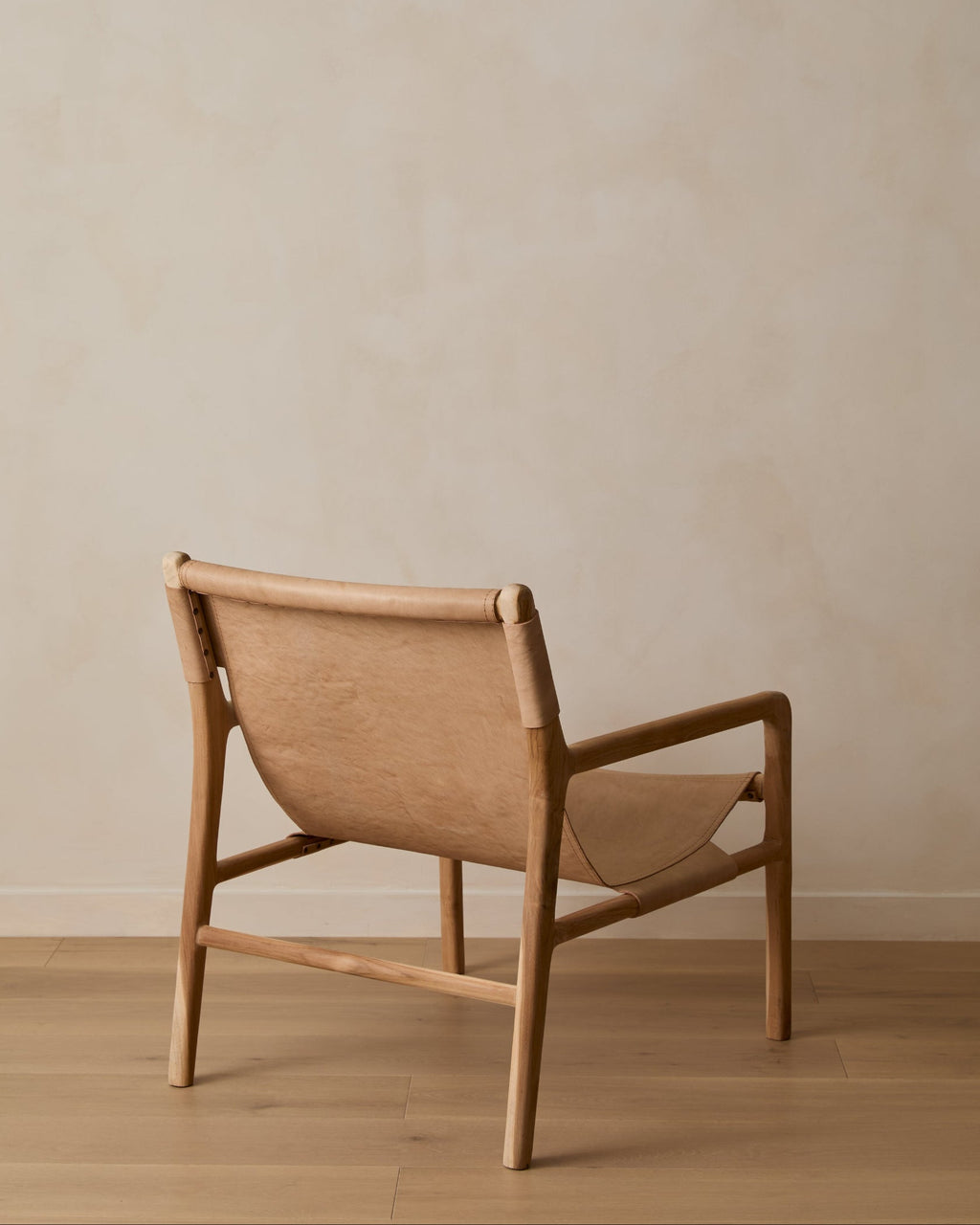 Beige leather sling lounge chair with carved teak frame, second quality with natural variations