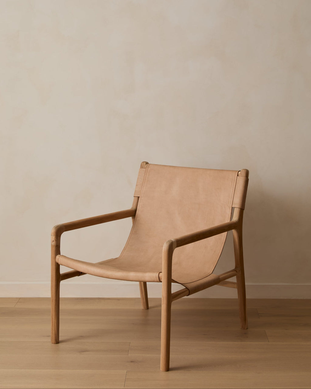 Beige leather sling lounge chair with carved teak frame, second quality with natural leather variations