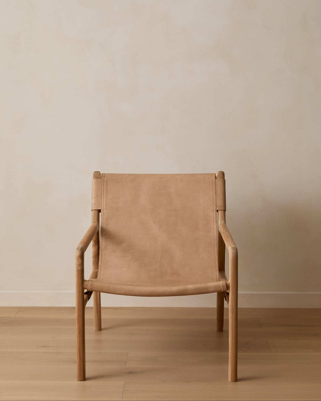 Modern leather sling lounge chair with teak frame and beige leather upholstery