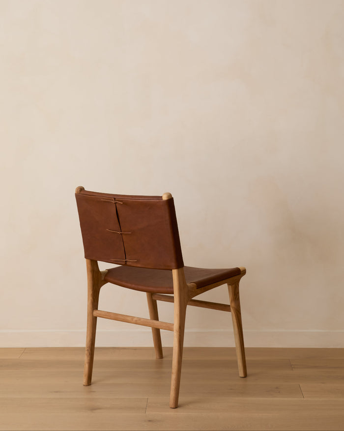 Sofia Dining Chair with saddle leather and back ties against a lime washed wall and white oak floors. Saffron and Poe