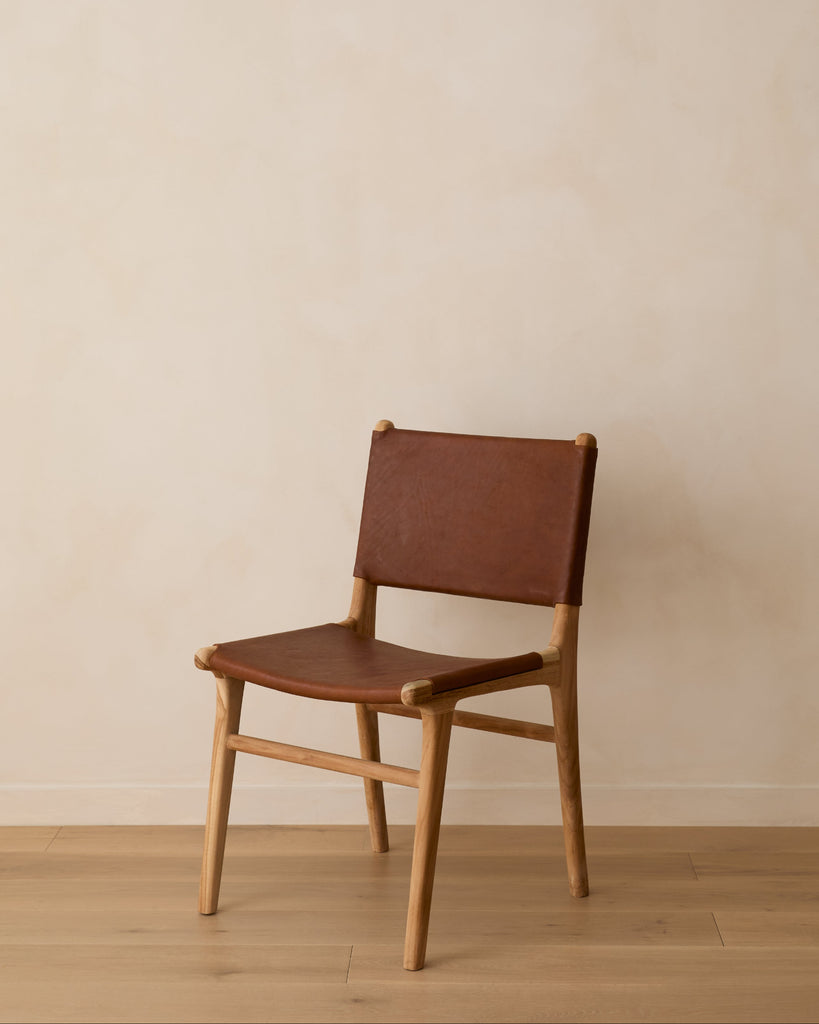 Sofia Dining Chair with saddle leather and back ties against a lime washed wall and white oak floors. Saffron and Poe