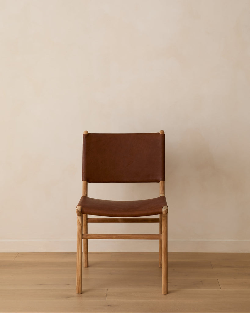 Sofia Dining Chair with saddle leather and back ties against a lime washed wall and white oak floors. Saffron and Poe
