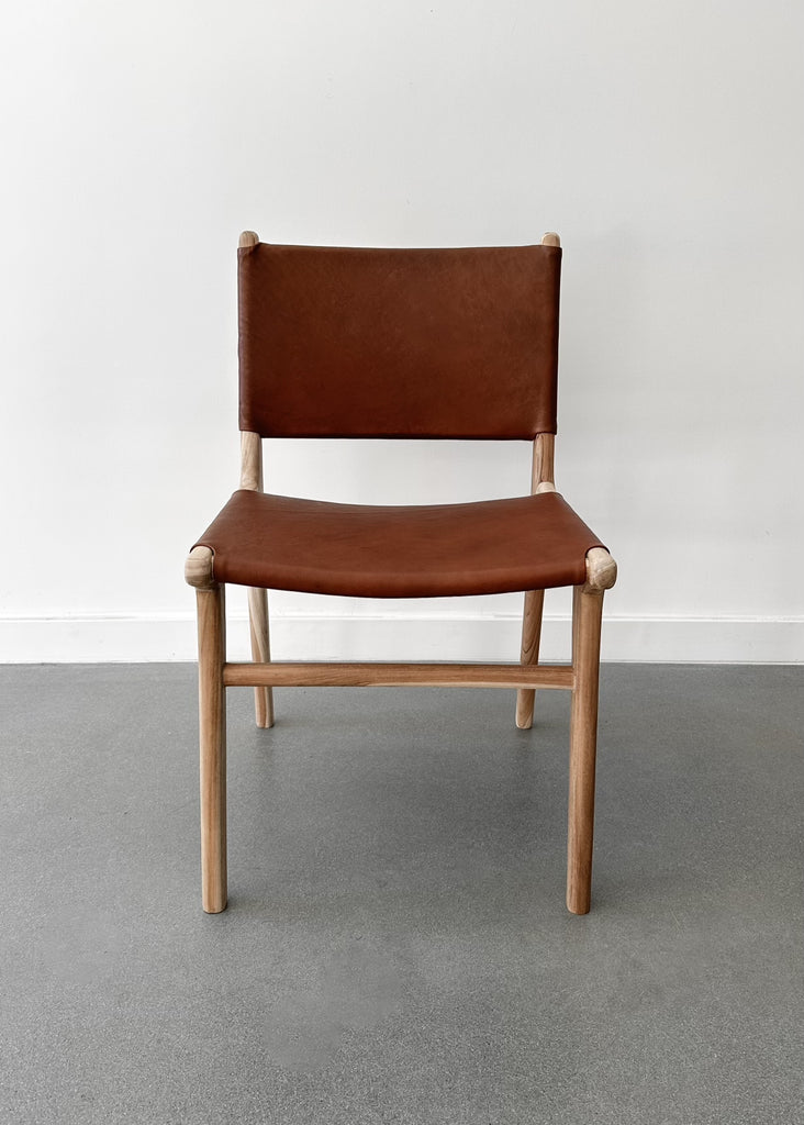 Our Stretched Leather and Teak Wood Sofía Dining Chair shot straight on with a white background. - Saffron + Poe
