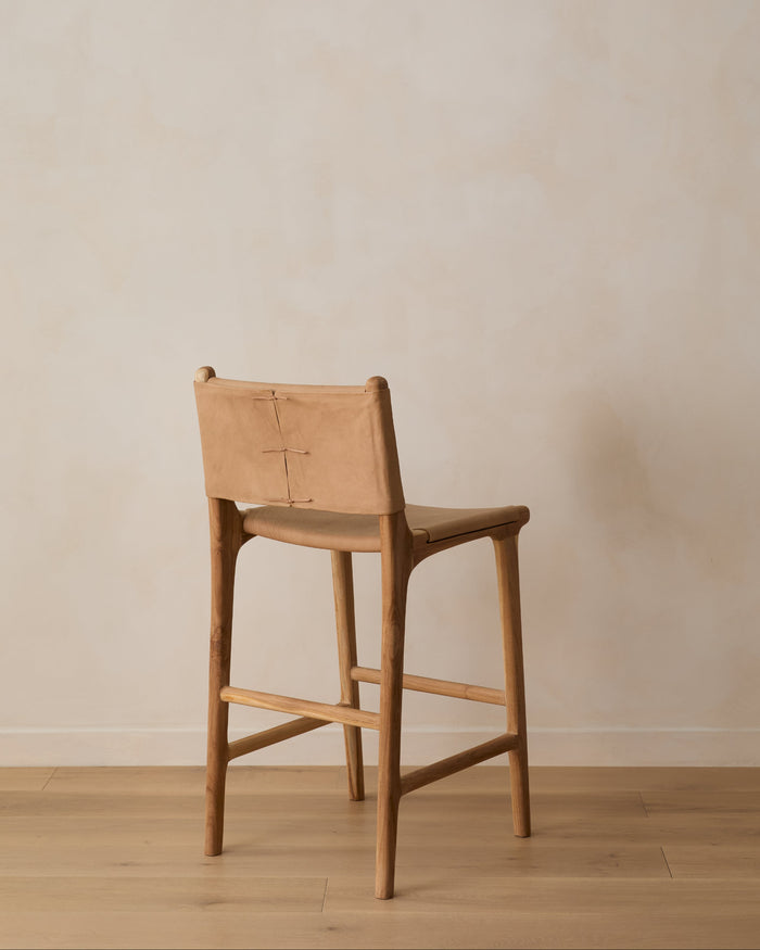 Smooth Leather and Teak Sofia Counter stool with back ties against a lime washed wall with white oak floor. Saffron and Poe