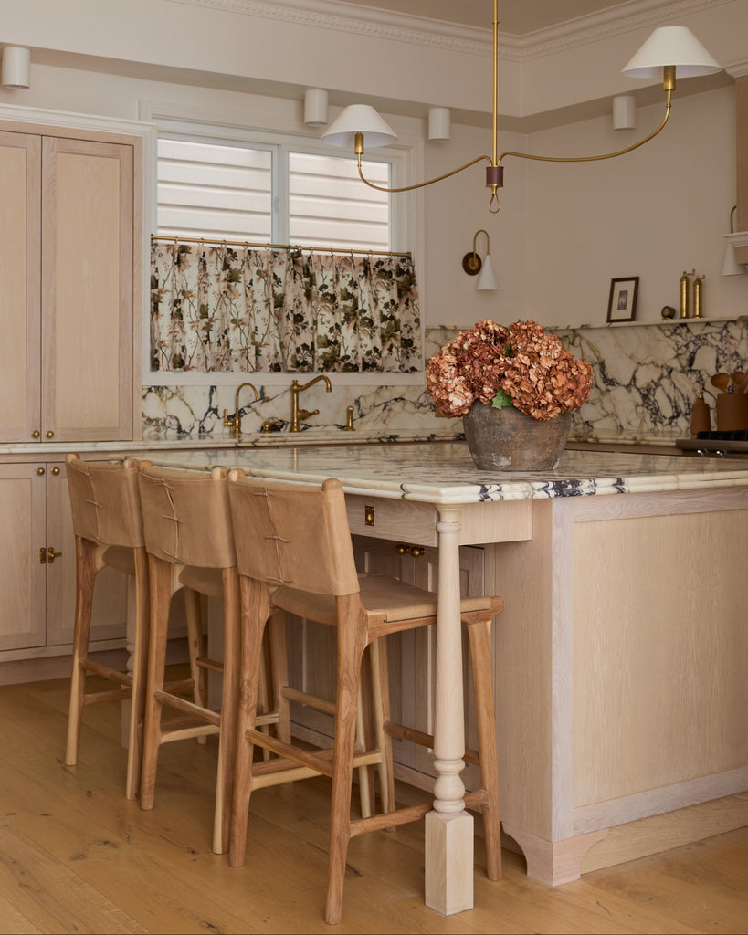 Smooth Leather and Teak Sofia Counter stool with back ties in marble kitchen with white oak cabinets and floors. Saffron and Poe