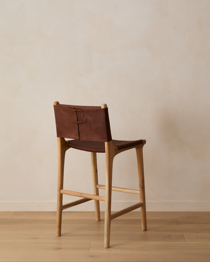 Sofia Counter Stool with saddle leather and back ties against a lime washed wall and white oak floors. Saffron and Poe