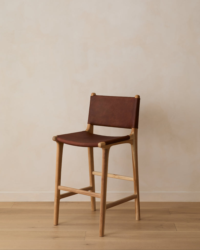 Sofia Counter Stool with saddle leather and back ties against a lime washed wall and white oak floors. Saffron and Poe