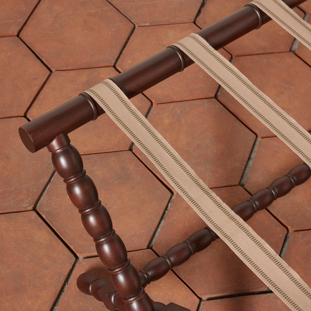 Somerset Luggage Rack close up detail of mahogany bobbin legs and beige cotton straps on a terracotta tile floor.