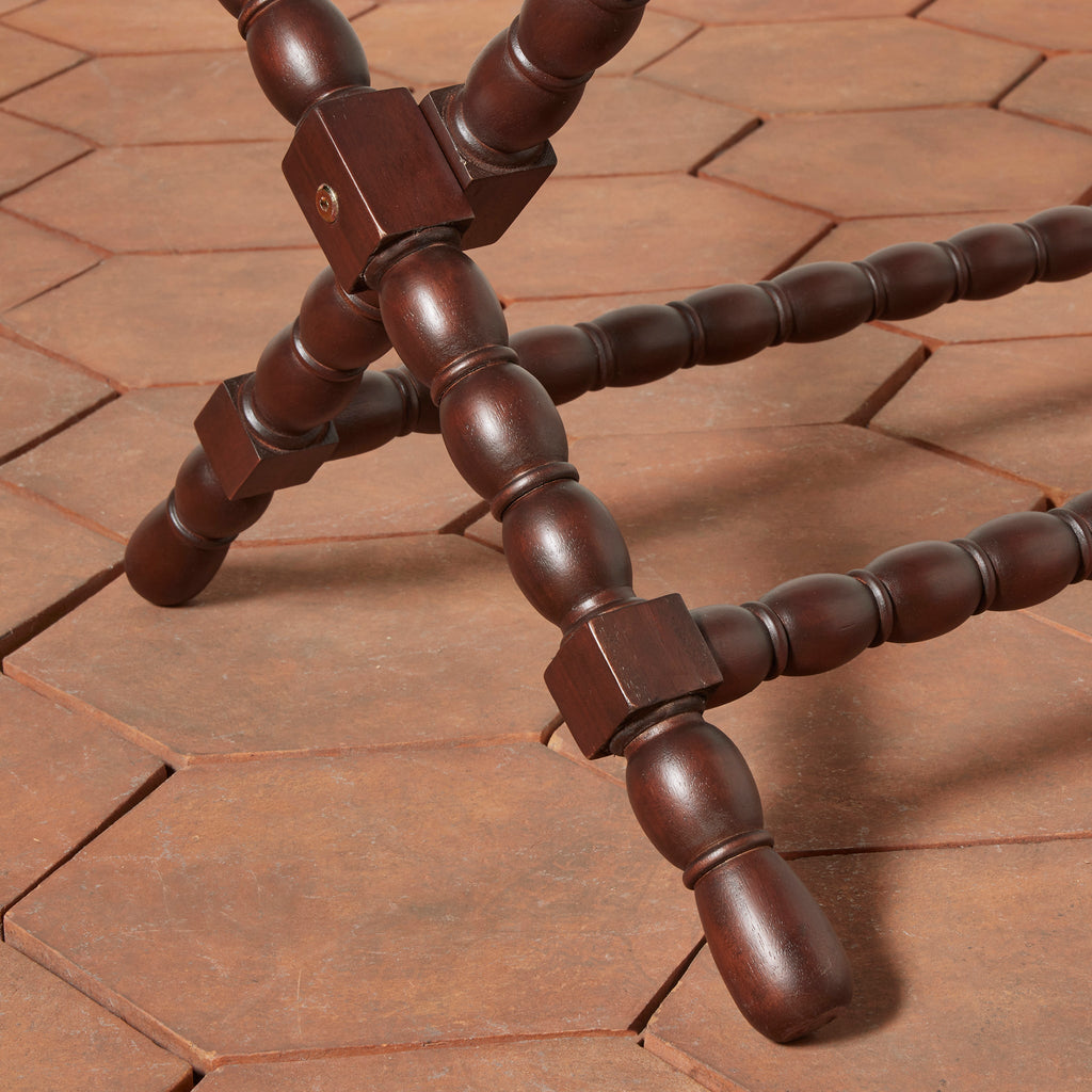 Close-up of bobbin leg detail on Somerset Luggage Rack against hexagon terracotta floor tile. 