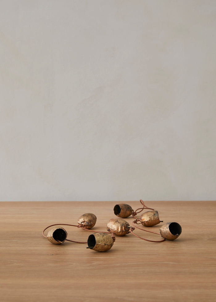 Vintage string of bells on a wooden surface with a limewash background
