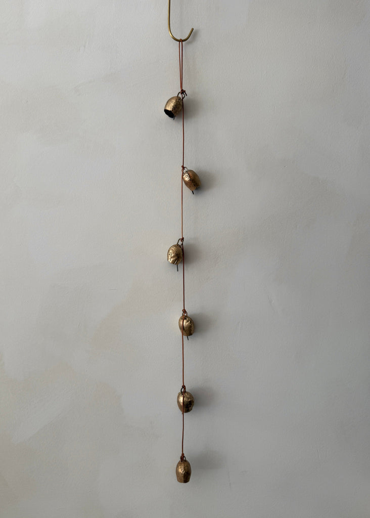String of small vintage brass bells on a white background