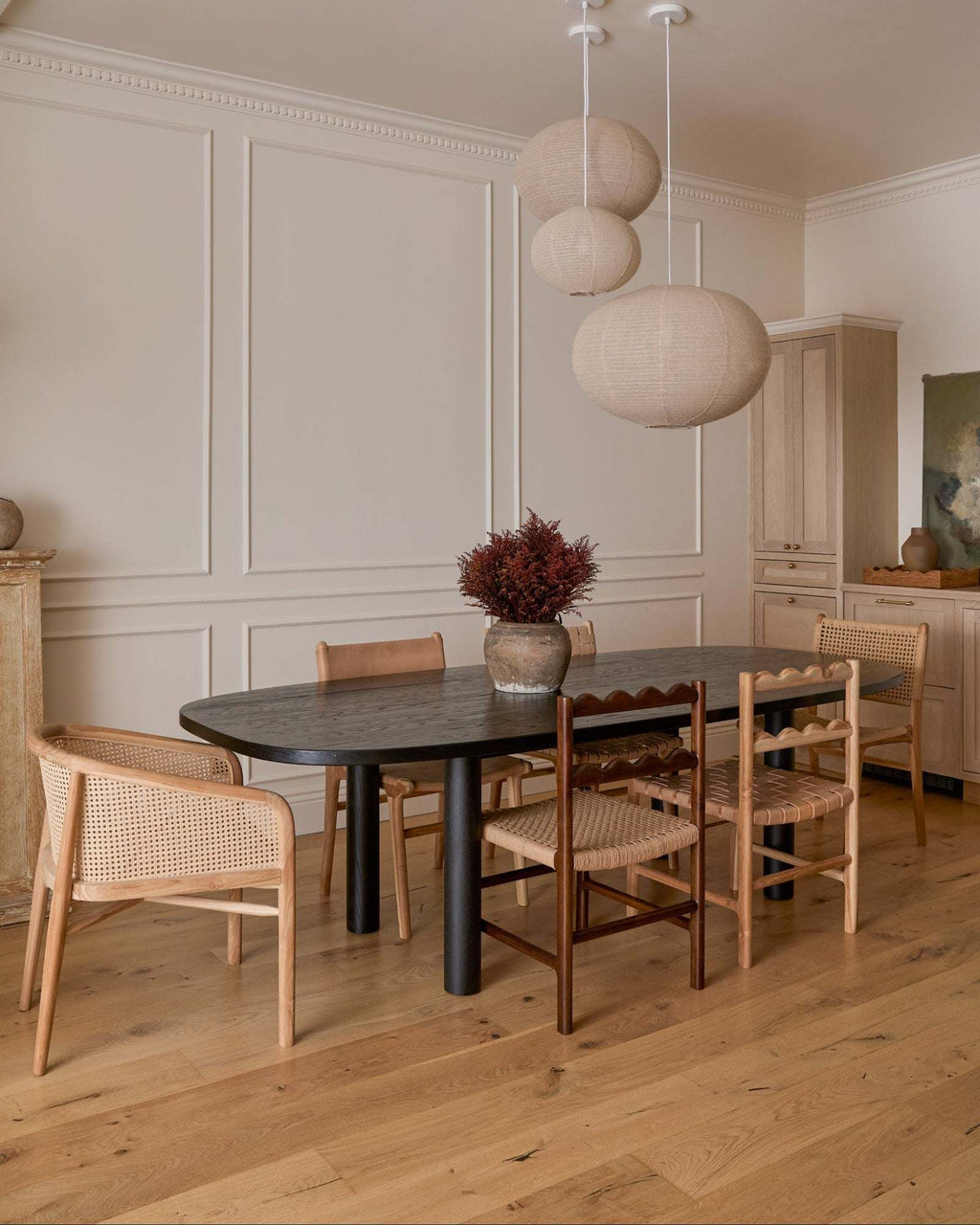 Dining room with a black table and teak dining chairs in a well-lit room.