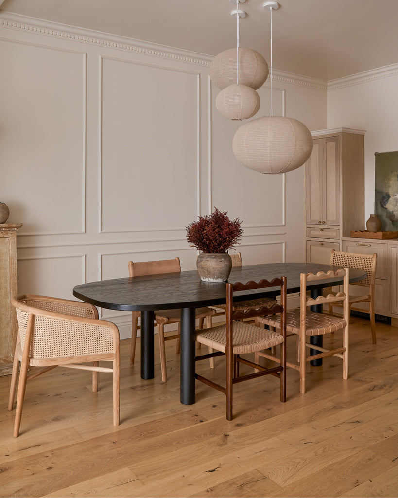 Dining room with a black table and teak dining chairs in a well-lit room.