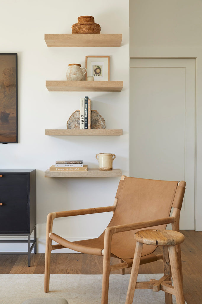 Styled Photo of Leather Sling Lounge Chair in a living room setting with floating shelves that include Italian Confit Clay Pot, Tenganan Stacking Baskets, and Vintage Stool. - Saffron and Poe