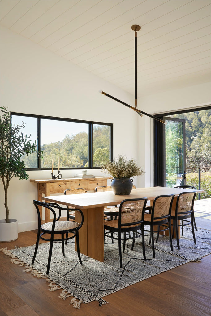 Styled photo of Live Edge Oak Dining Table in a dining room setting with black dining chairs, Moroccan Flat Weave Kilim Rug, Vintage Storage Console, and Antique Clay Pot. - Saffron and Poe.