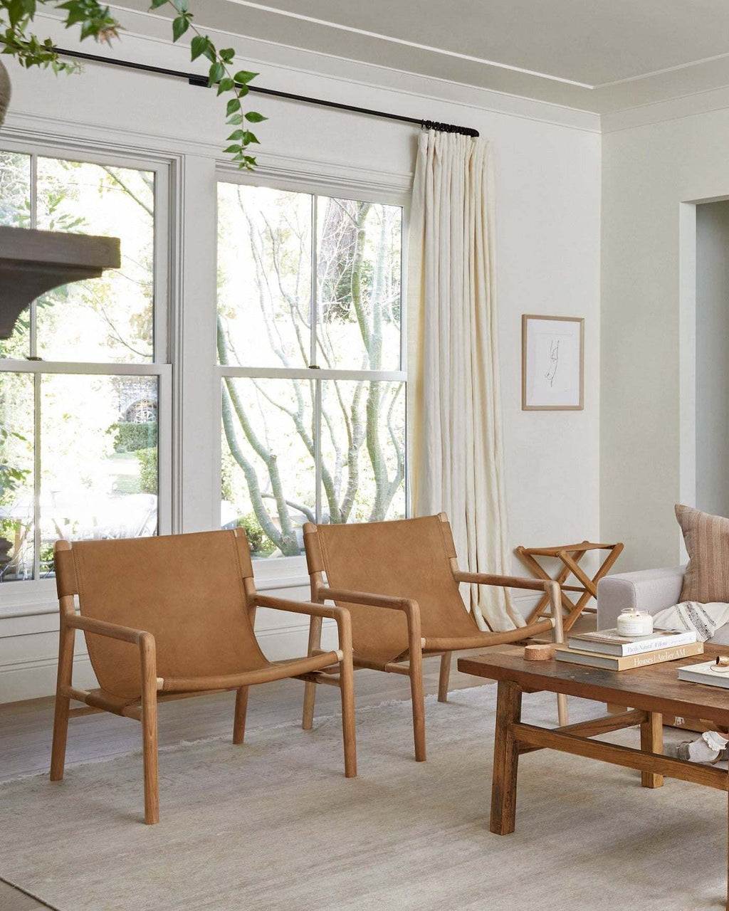 Modern leather sling lounge chair with carved teak frame and beige leather upholstery