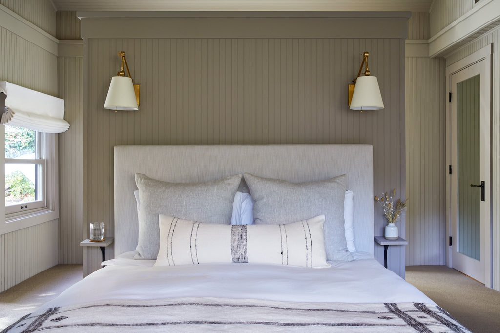 Grey Stripe Handwoven Colombian Lumbar Pillow styled in a bedroom setting with Linen Pillow and Ceramic Bud Vase. - Saffron and Poe