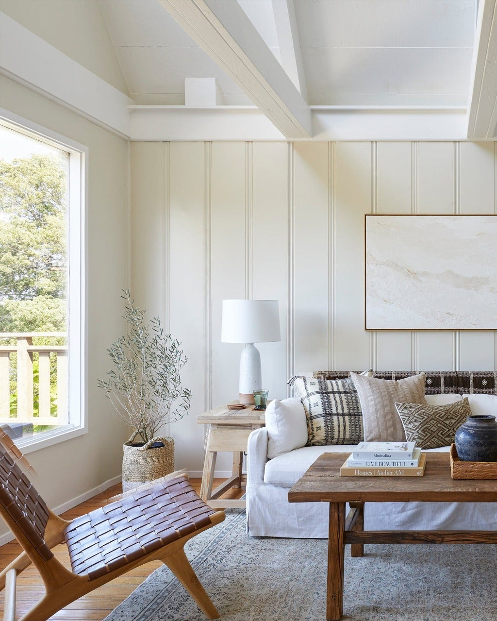 Woven leather lounge chair with saddle-colored straps and teak wood frame in bright living room setting