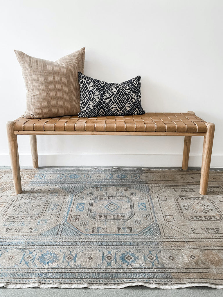 Styled 48" woven leather strap bench in beige with vintage Turkish oushak rug and two pillows. Handcrafted in Bali. - Saffron and Poe