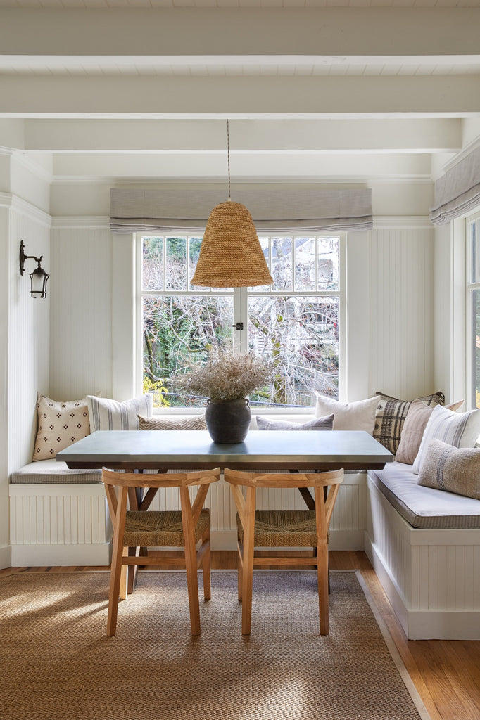 Woven Wishbone Dining Chair styled in a dining room with Antique Clay Pot, Brown Checkered Pillow, Bhujodi Pillow, and Woven Pendant. - Saffron and Poe