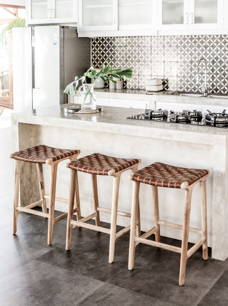 Open white kitchen styled with three counter height Backless Woven Leather Counter dining stools. Handmade in Bali using Teak wood and vegetable-tanned leather imported from Java. - Saffron and Poe