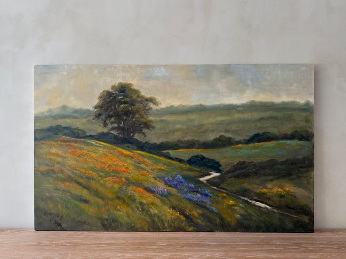 Vibrant oil landscape painting of rolling flower fields with a lone tree in the distance and stream running through - Saffron and Poe.